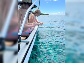 Two children lean over the side of a boat, captivated by the clear turquoise waters below — a perfect moment for fishing or snorkeling adventures.