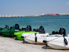 A row of colorful kayaks lined up on the beach, ready for adventure in the clear waters — perfect for water sports enthusiasts.