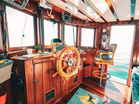 A cozy interior view of a boat's helm, featuring polished wood finishes and essential navigation equipment, perfect for a comfortable sailing experience.