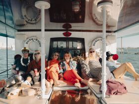 A lively group enjoys a fun day on the boat, relaxing and sipping drinks while soaking up the sun — perfect for celebrations and gatherings on the water.