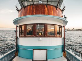 A cozy view of the helm area inside a boat, featuring smiling guests enjoying the scenic waterfront. Perfect for capturing the essence of a relaxing boat trip.