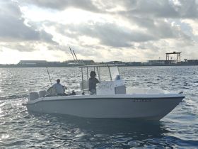 A fishing boat named 'Salty Tale' is underway with two people onboard, showcasing a perfect day for fishing adventures on the water.