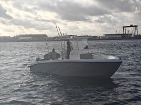 A sleek speedboat named 'Salty Tale' navigates the waters, showcasing its design against a backdrop of cloudy skies and distant structures.