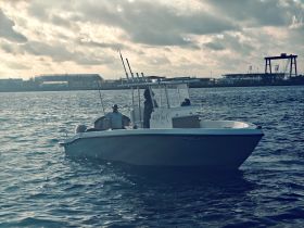 A sleek speedboat named 'Salty Tale' navigates the waters, showcasing its design and functionality against a backdrop of clouds and distant structures.