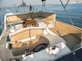 A spacious interior view of a boat featuring comfortable seating and a helm, perfect for relaxing while cruising on the water.