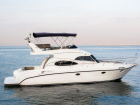 A sleek yacht is docked on calm waters, showcasing its elegant design and spacious upper deck, perfect for luxury cruising.