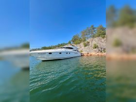 A stunning yacht named Rozzo docked in serene waters, surrounded by lush greenery and rocky shores, perfect for a relaxing getaway.