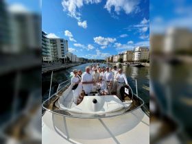 A lively group of guests celebrates aboard a stylish boat, enjoying drinks and the beautiful waterfront scenery — perfect for memorable gatherings and events.