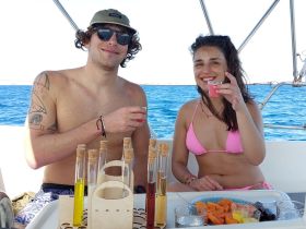 A cheerful couple enjoys cocktails and snacks aboard a boat, capturing the essence of a fun day on the water.