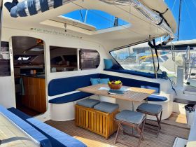 A beautifully designed interior of a catamaran featuring a cozy dining area and comfortable seating, perfect for relaxing and enjoying meals while on the water.