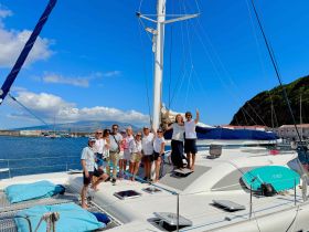 A cheerful group of friends poses aboard a catamaran in a picturesque harbor, capturing the joy of their sailing adventure together.