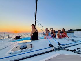 A joyful group enjoys a stunning sunset aboard a catamaran, capturing the essence of family bonding and celebration on the water.