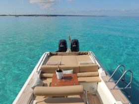 A luxurious lounge area on a boat featuring comfortable seating and a champagne bucket, perfect for relaxing while enjoying the stunning turquoise waters.