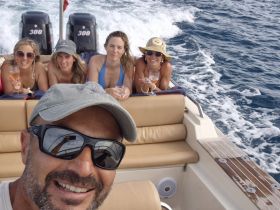 A joyful group of friends enjoys a fun day on the water, sipping cocktails and soaking up the sun aboard a speedboat.