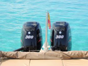 Close-up view of twin 300 HP outboard motors on a boat, showcasing essential marine equipment against a backdrop of clear turquoise waters.