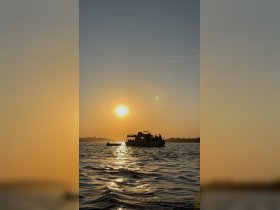 A picturesque sunset view featuring a boat with guests silhouetted against the vibrant sky, perfect for capturing memorable moments on the water.