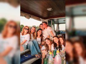 A joyful group of friends poses together inside a boat, celebrating their time on the water with drinks and laughter — perfect for memorable outings and gatherings.