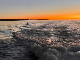 A stunning sunset over calm waters, showcasing the beautiful colors of the sky reflecting on the surface — perfect for serene evening boat trips.