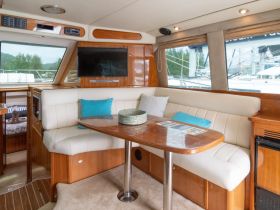 A cozy interior view of a yacht's cabin featuring comfortable seating and a dining area, perfect for relaxing during your boating adventures.