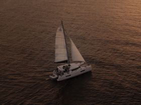 A stunning aerial view of a catamaran sailing gracefully across the water, showcasing its sleek design and the beauty of the open sea.