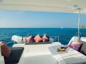 A beautifully arranged table with cocktails and a selection of snacks on a yacht's deck, perfect for enjoying a relaxing day on the water.