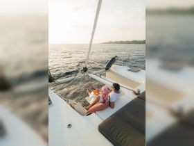 A couple enjoys a romantic moment on the deck of a yacht, soaking in the sunset views over the water — an ideal setting for intimate getaways.