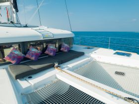 A cozy lounge area on a catamaran featuring colorful cushions and a spacious seating arrangement, perfect for relaxing while enjoying the ocean views.
