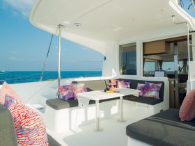 A beautifully designed lounge area inside a boat, featuring comfortable seating and vibrant cushions, perfect for relaxing while enjoying the ocean views.