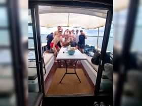 A lively group of friends gathers on a boat, enjoying drinks and snacks — perfect for a fun day out on the water.