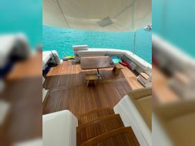 A spacious interior view of a boat's seating area featuring a wooden table and comfortable lounge space, perfect for relaxing while enjoying the surrounding turquoise waters.