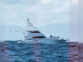 A stunning side view of a luxurious yacht cruising through the open waters, showcasing its sleek design and fishing equipment.