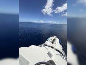 A stunning view from the front of a yacht cruising through calm blue waters under a clear sky, perfect for serene boating adventures.