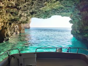 A stunning view from inside a boat looking out through a natural cave, showcasing the beautiful turquoise waters and rocky coastline — perfect for exploring hidden gems on your boating adventure.