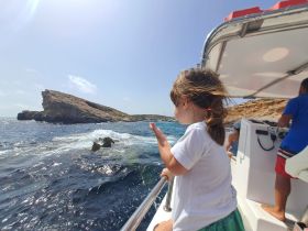 A child enjoys the ocean breeze while exploring the coastline from a boat, capturing the essence of adventure on the water.