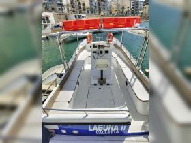 Interior view of a boat's helm and seating area, showcasing the console and spacious layout, ideal for navigation and comfort on the water.