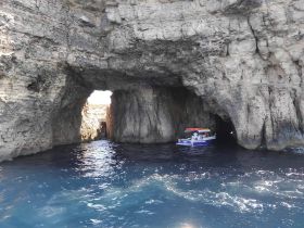 A boat navigates through a stunning cave formation, showcasing the breathtaking coastal scenery — a perfect adventure for exploring hidden gems on the water.