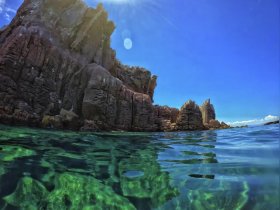 A stunning view of rocky coastline and crystal-clear waters, showcasing the natural beauty of the area — perfect for eco tours and scenic boat trips.