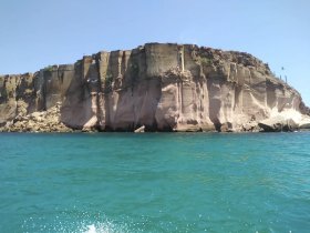 A stunning view of a rocky coastline with vibrant turquoise waters, perfect for showcasing the natural beauty of the area during a boating adventure.