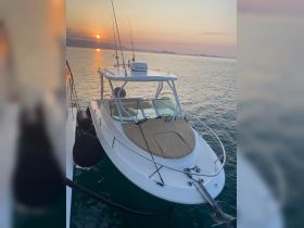 A stunning view of a speedboat docked at sunset, showcasing its sleek design against a picturesque backdrop of calm waters and distant mountains.