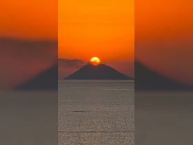 A stunning sunset over a tranquil island, creating a picturesque scene perfect for romantic getaways or serene boat trips.