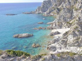A stunning aerial view of a secluded beach with crystal-clear waters and rocky coastline, perfect for exploring and enjoying nature's beauty.