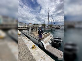 A man gives a thumbs up next to a stylish boat docked at the marina, showcasing the perfect spot for a day on the water.