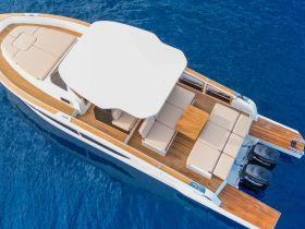 An aerial view of the spacious interior lounge area of a boat, featuring comfortable seating and a shaded area, perfect for relaxing on the water.