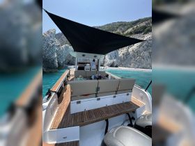 The interior of a boat showcases comfortable seating and a helm area, perfect for relaxing while enjoying the stunning coastal views.