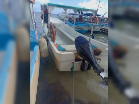 A view of a small boat docked in shallow waters, showcasing its structure and motor, ideal for fishing or short trips.