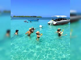 A lively group enjoys a refreshing day in the crystal-clear waters, sipping cocktails and having fun under the sun — the perfect beach getaway.