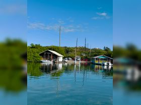 A scenic view of a waterfront area with houses and boats, reflecting in calm waters, creating a tranquil atmosphere.