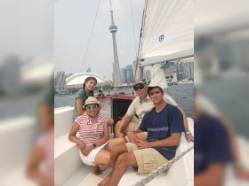 A family enjoys a sailing trip in Toronto, with the iconic CN Tower in the background, capturing a perfect moment of togetherness on the water.