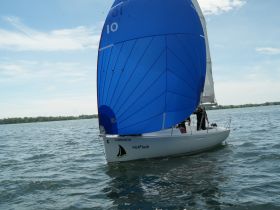 A sleek sailboat with a vibrant blue sail glides through the water, showcasing the excitement of sailing adventures on a sunny day.