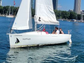A lively group enjoys a sailing experience aboard the 'HotFlash' in clear waters, perfect for summer adventures on the water.